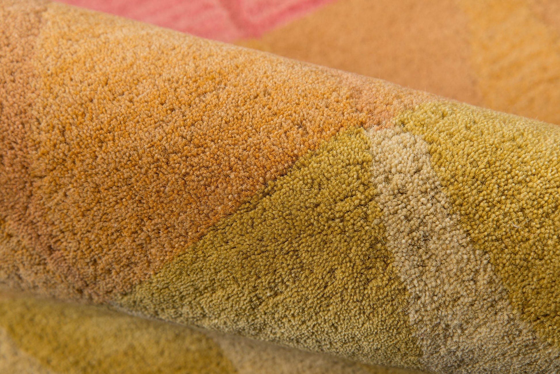 Close-up of a multicolored tufted rug in orange, yellow, green and pink tones with a soft pile.