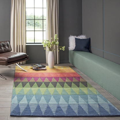 Multicolor geometric triangle rug with blue-green-pink gradient in a living room beside a green bench and leather chair.