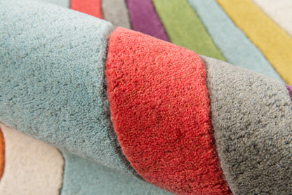 Close-up of a plush multicolor striped shag rug with blue, red, gray and pastel shades; soft, thick pile.