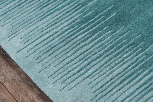 Turquoise ribbed area rug with raised parallel ridges on a brown wooden floor.