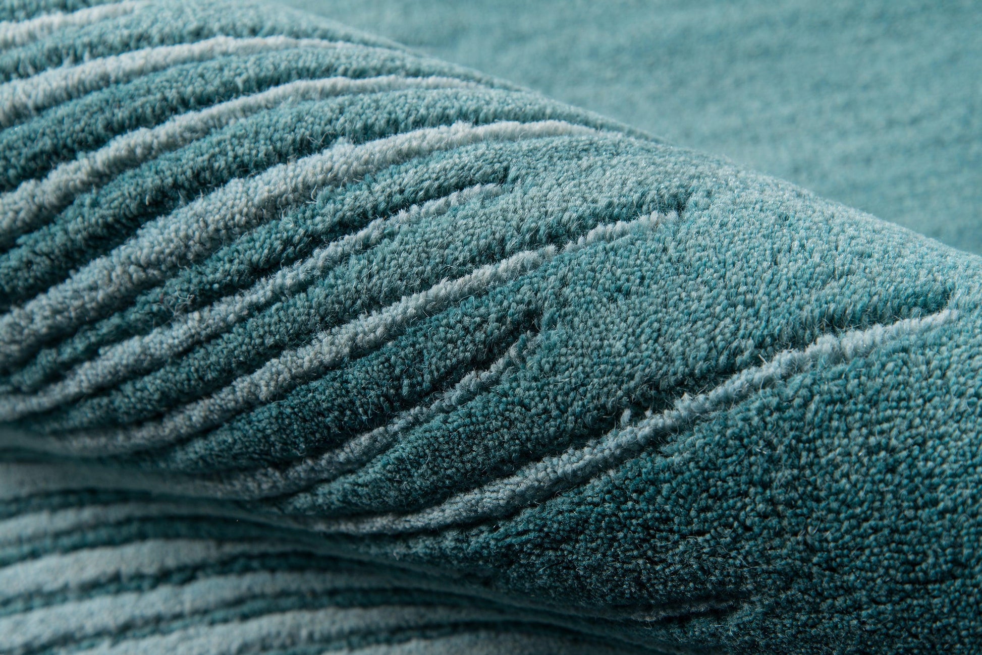 Teal blue rug with plush pile and diagonal ribbed texture.