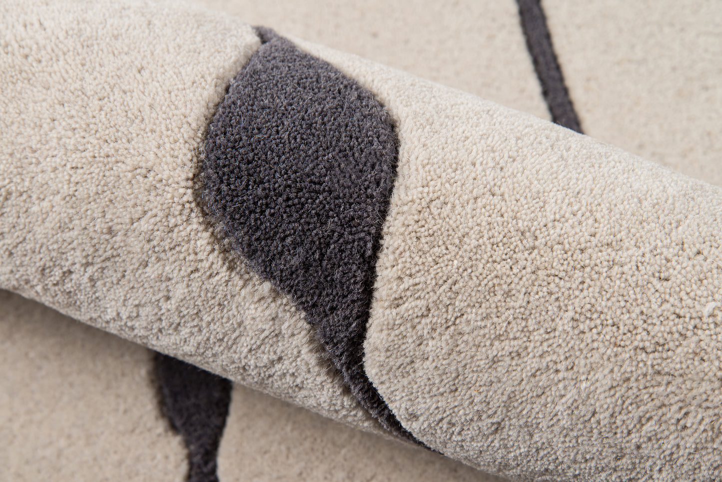 Beige plush rug with dark gray curved stripe, high-pile texture, rolled rug.