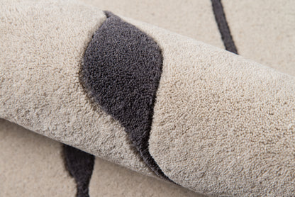 Beige plush rug with dark gray curved stripe, high-pile texture, rolled rug.