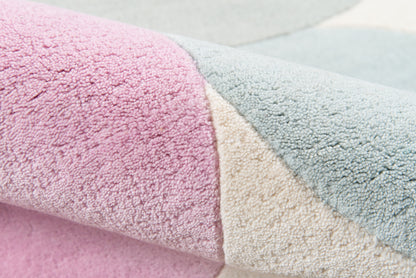Close-up of a pastel pink, beige and light blue plush rug with soft chenille pile and geometric color blocks.