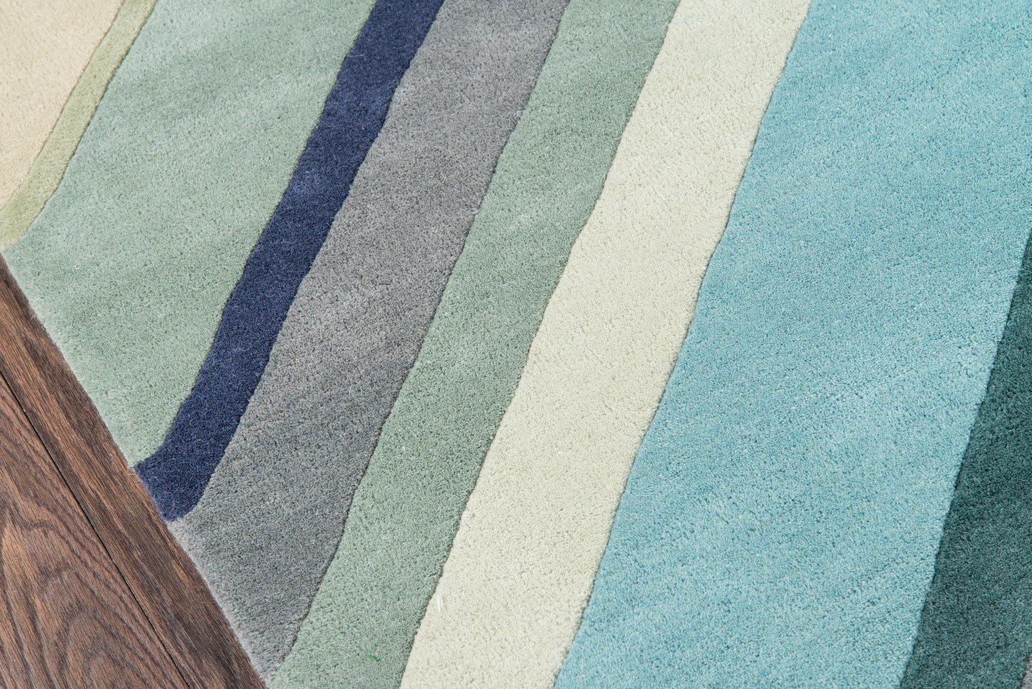 Soft woven 2' x 8' runner rug with diagonal stripes in blues, teals, mint greens & cream; wood-toned corner.