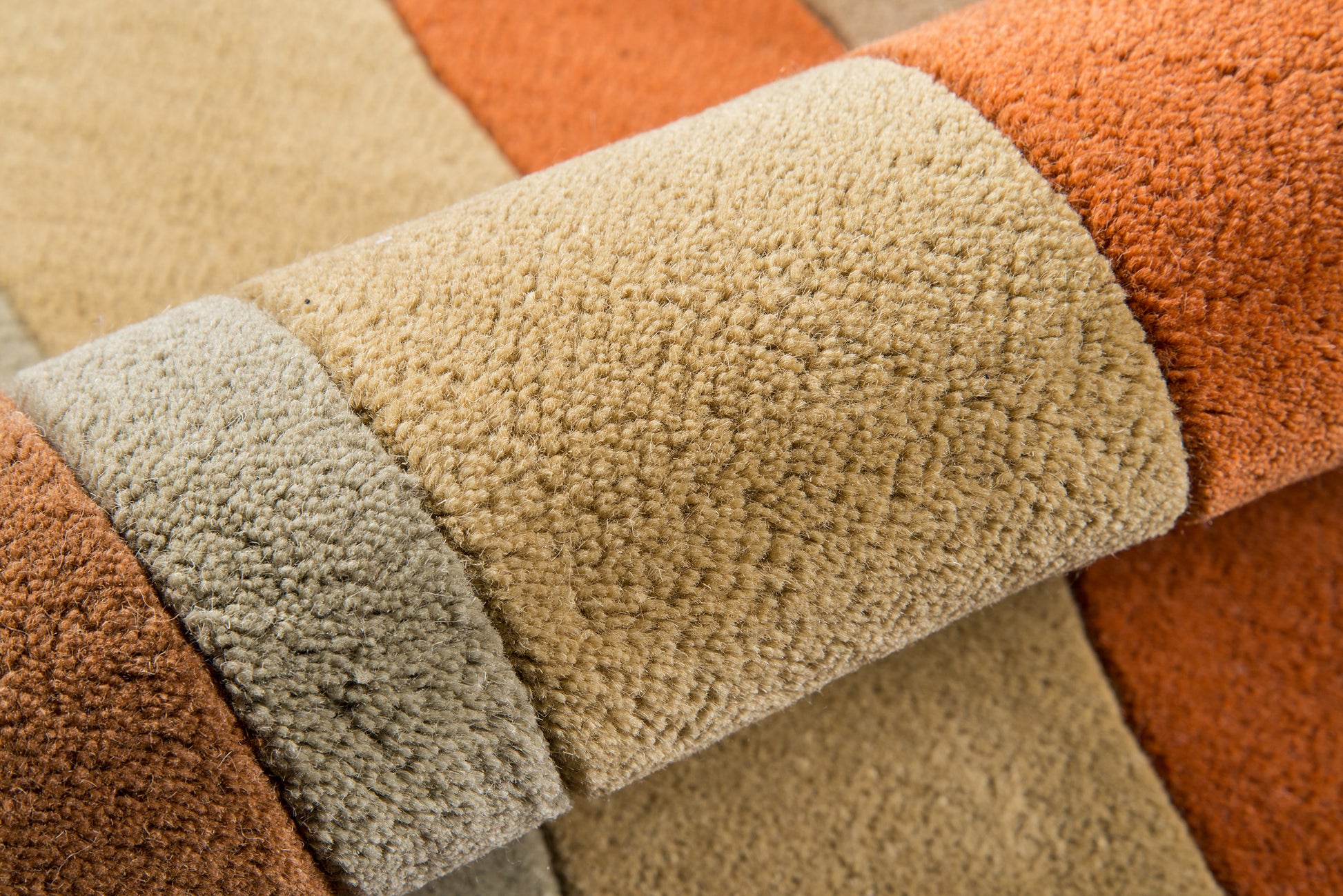 Close-up of a plush striped rug in tan, beige and orange with a soft textured pile.