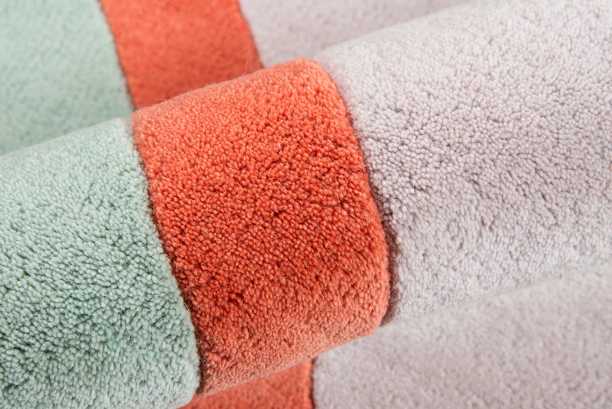 Pastel striped rug in mint green, coral orange, and light gray; rolled, plush pile, 9' x 12'.