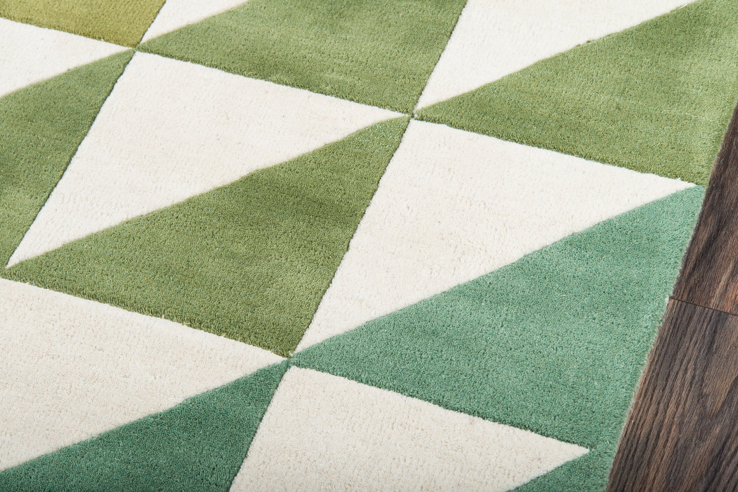 Geometric green and cream triangle rug with a diamond pattern on a wood floor.