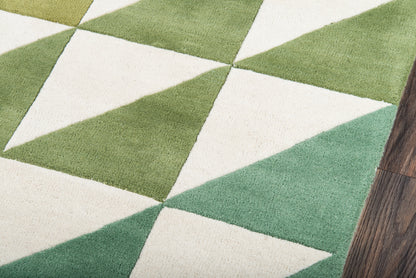 Geometric green and cream triangle rug with a diamond pattern on a wood floor.