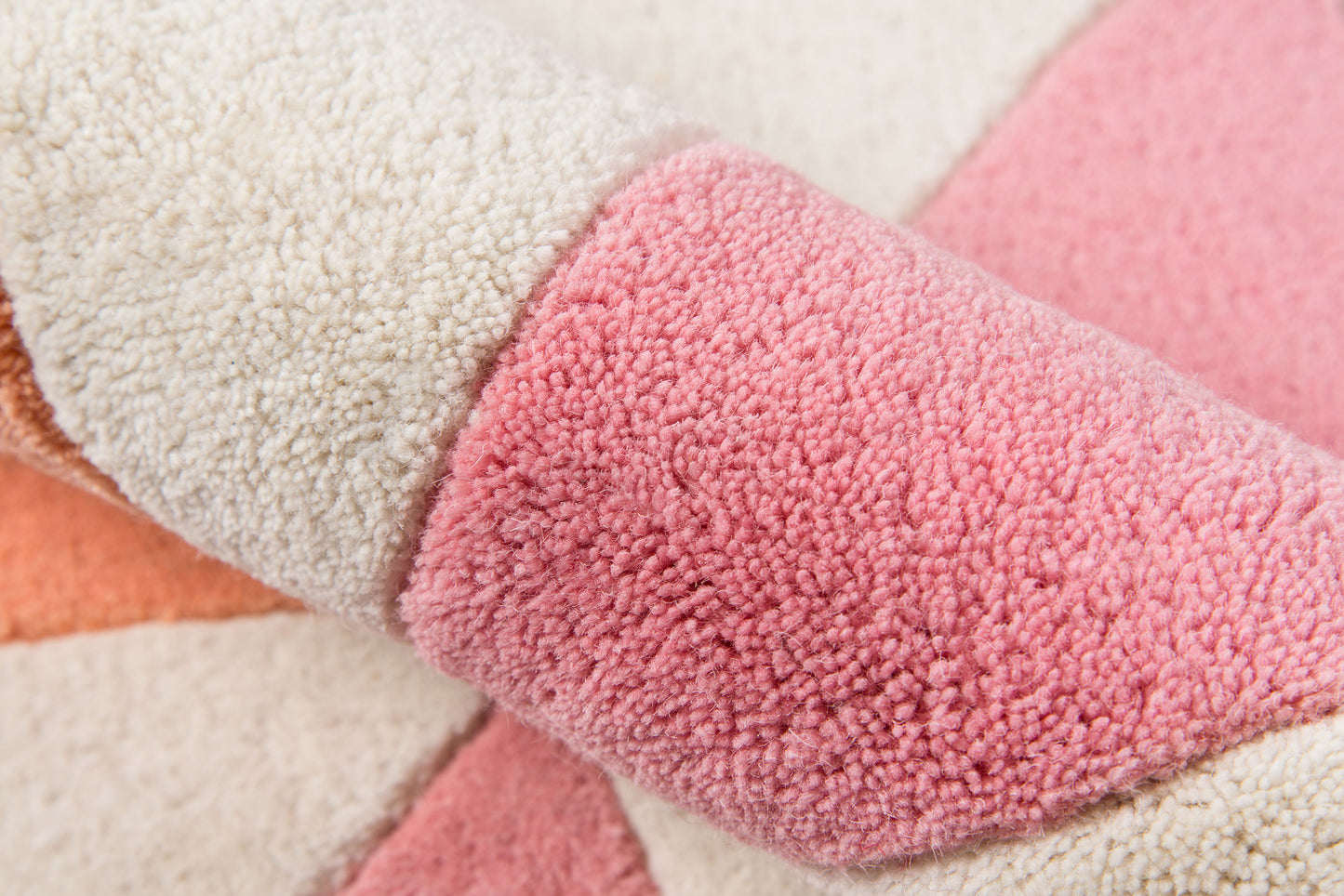Soft shag pile area rug in pink, cream, and peach color blocks with a plush, woven texture.