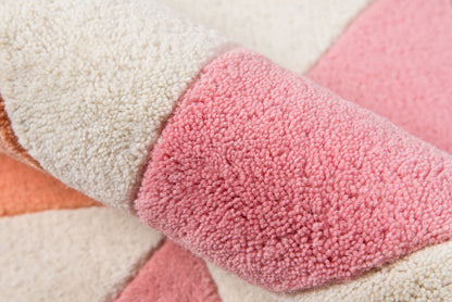 Soft shag pile area rug in pink, cream, and peach color blocks with a plush, woven texture.