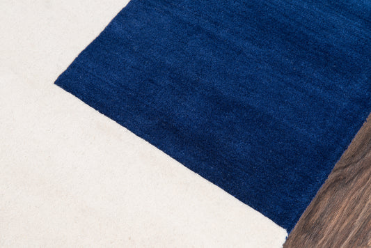Royal blue rectangular rug on light beige floor with wood edge.