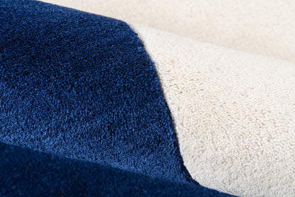 Close-up of navy blue and cream rug fabric with a soft loop pile and folded edge.