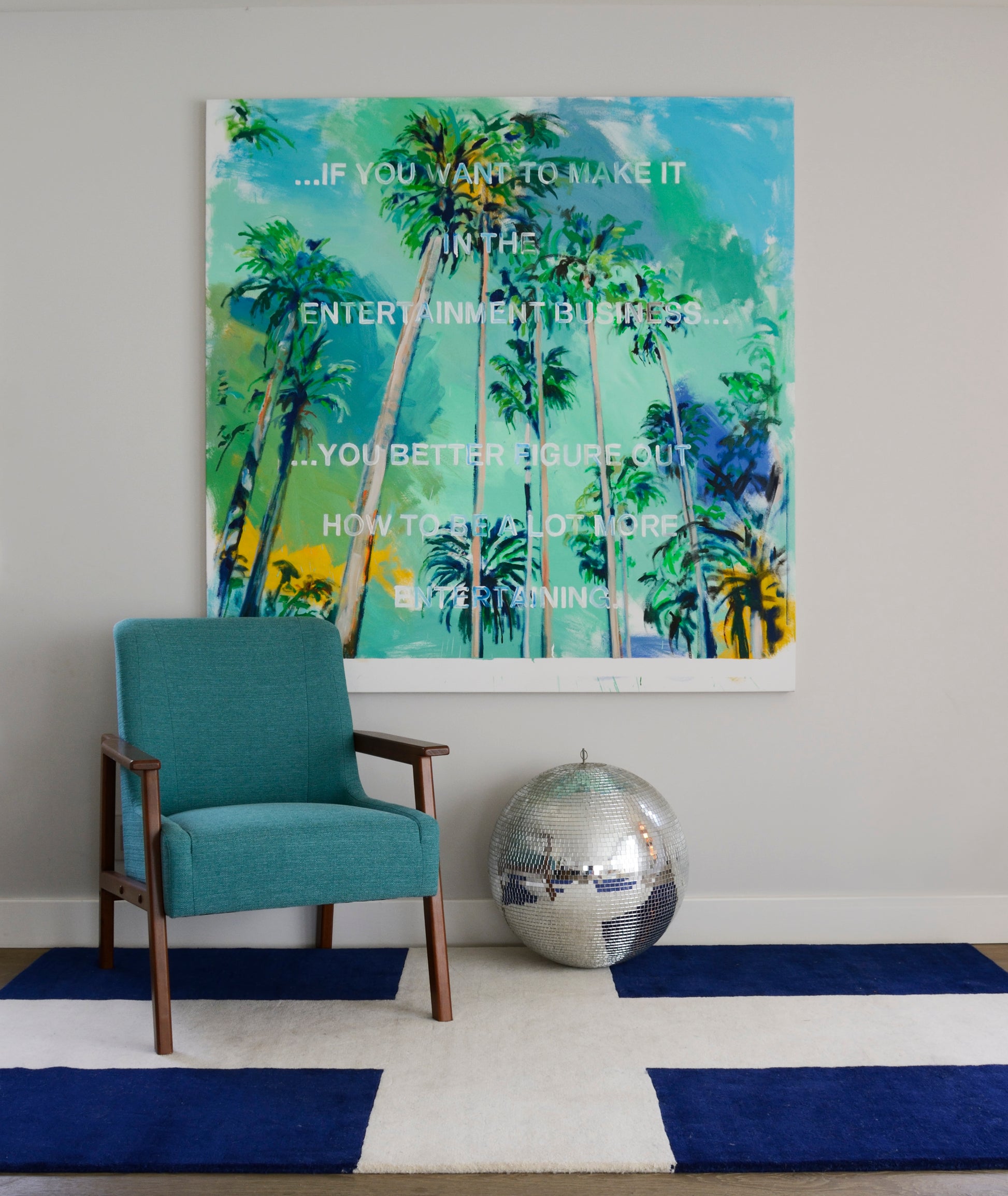 Blue-and-white striped rug with turquoise accents; silver globe and bright palm-tree wall art in the scene.