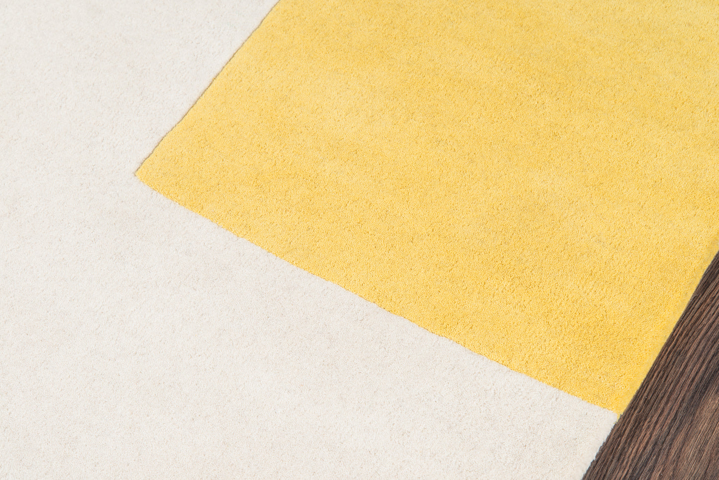 Yellow rug on a light textured floor with a dark wood corner; simple home decor accent, 5' x 8' rug.