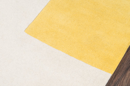 Yellow rug diagonally placed on pale beige surface with dark wood edging