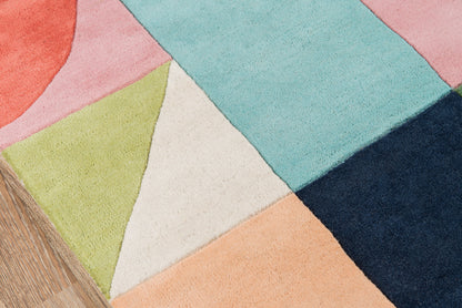 Geometric color-block rug with pink, peach, lime, cream, light blue, teal and navy on a wooden floor.