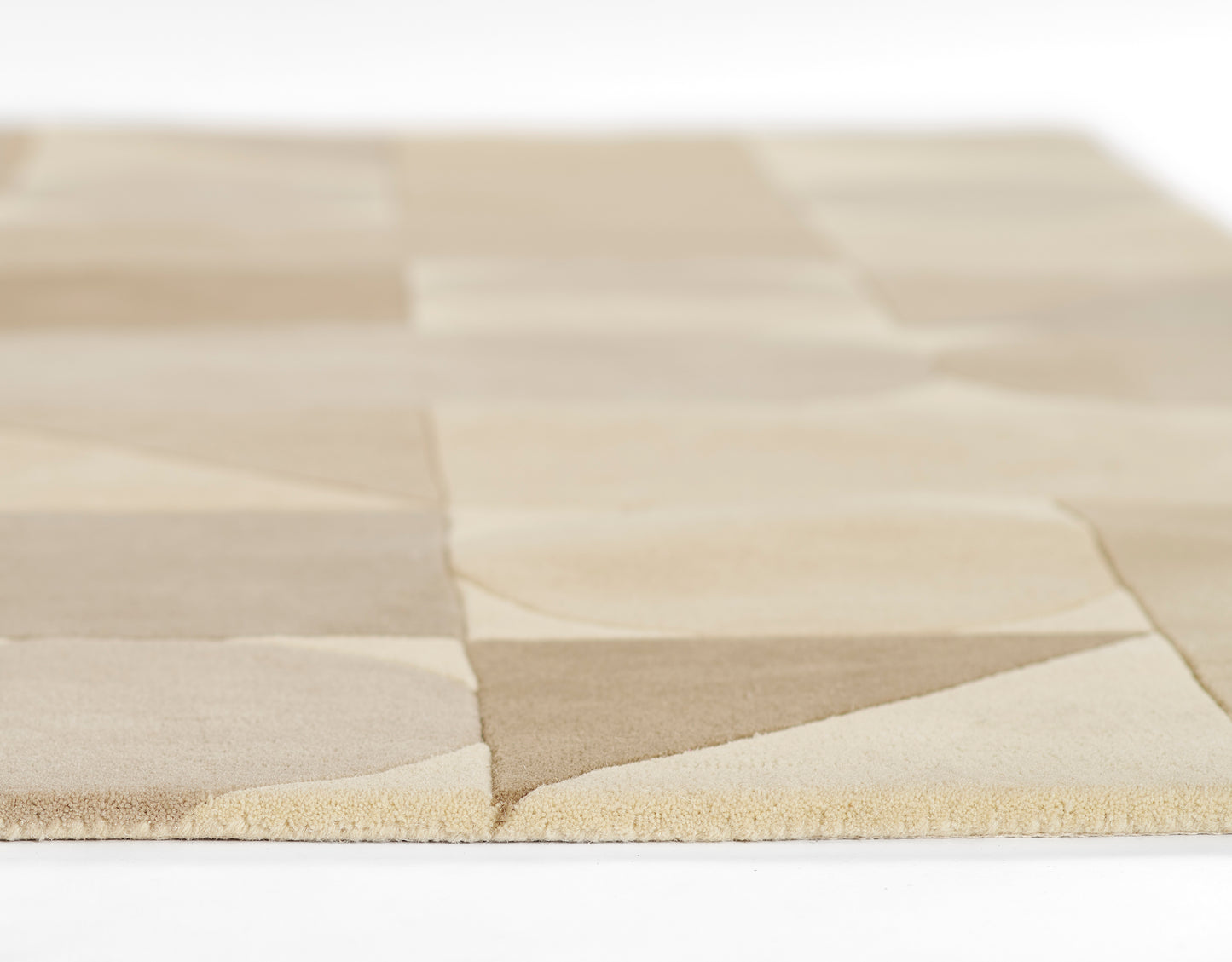 Beige patchwork rug with alternating light tan and cream squares, soft woven texture and fringe edge.