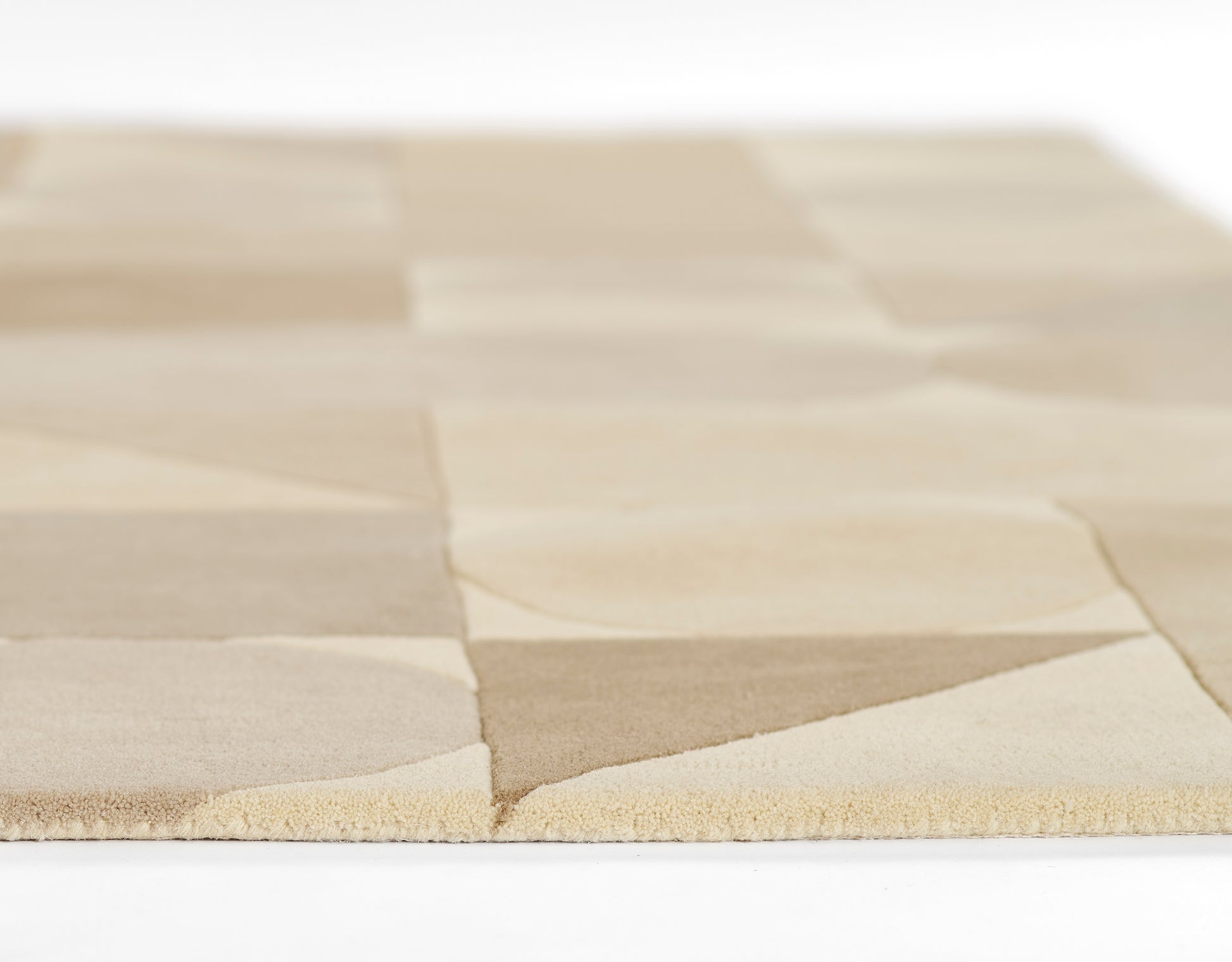 Beige patchwork rug with alternating light tan and cream squares, soft woven texture and fringe edge.