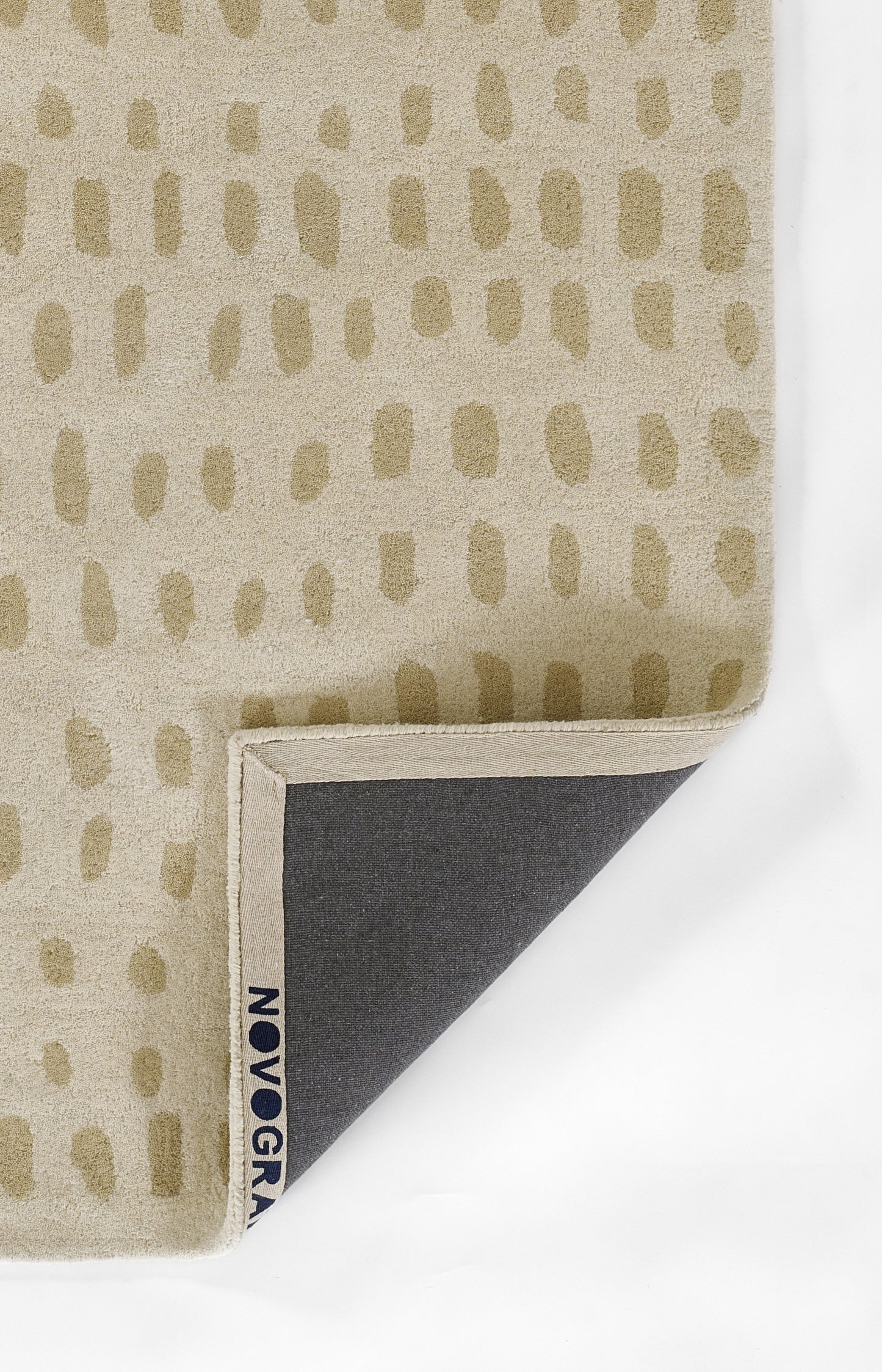 Beige fabric with tan oval dot pattern, folded corner reveals navy underside and small blue edge tag.