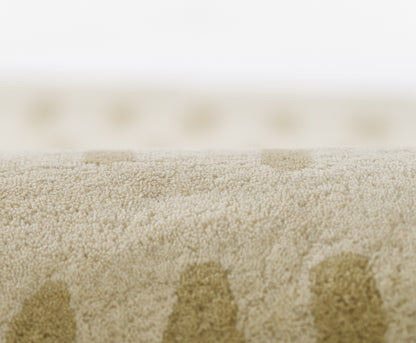 Beige plush rug with soft high-pile fibers and subtle circular darker dots.