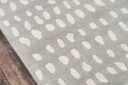 Gray rug with white irregular dot pattern on a wooden floor.