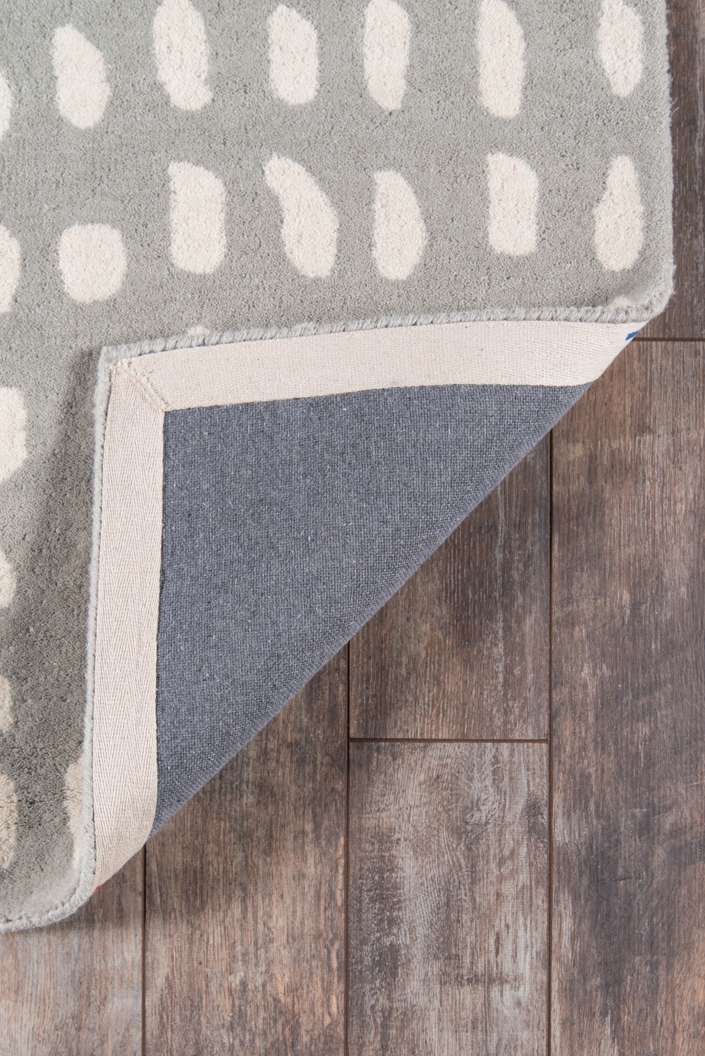 Grey modern runner with white rectangular dots and cream border; folded corner reveals blue-grey underside on wood floor.