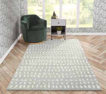 Gray rug runner with white dotted pattern on a herringbone floor; green velvet armchair, white side table, and plants by a window.