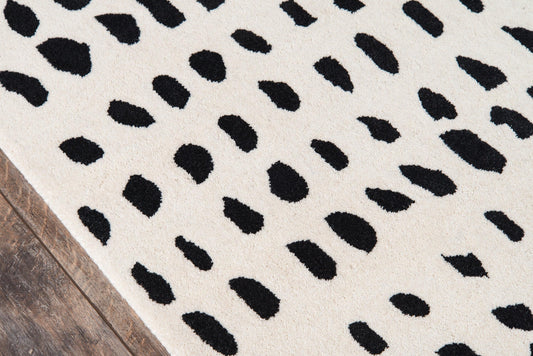 Ivory rug with irregular black Dalmatian-style spots on a wooden floor.