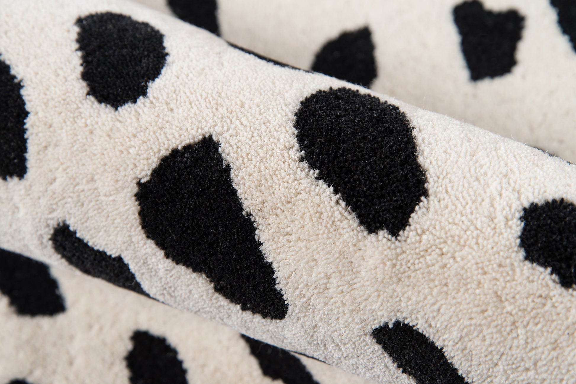 Beige plush sherpa rug runner with black irregular spots in a leopard pattern; 2' x 8'.