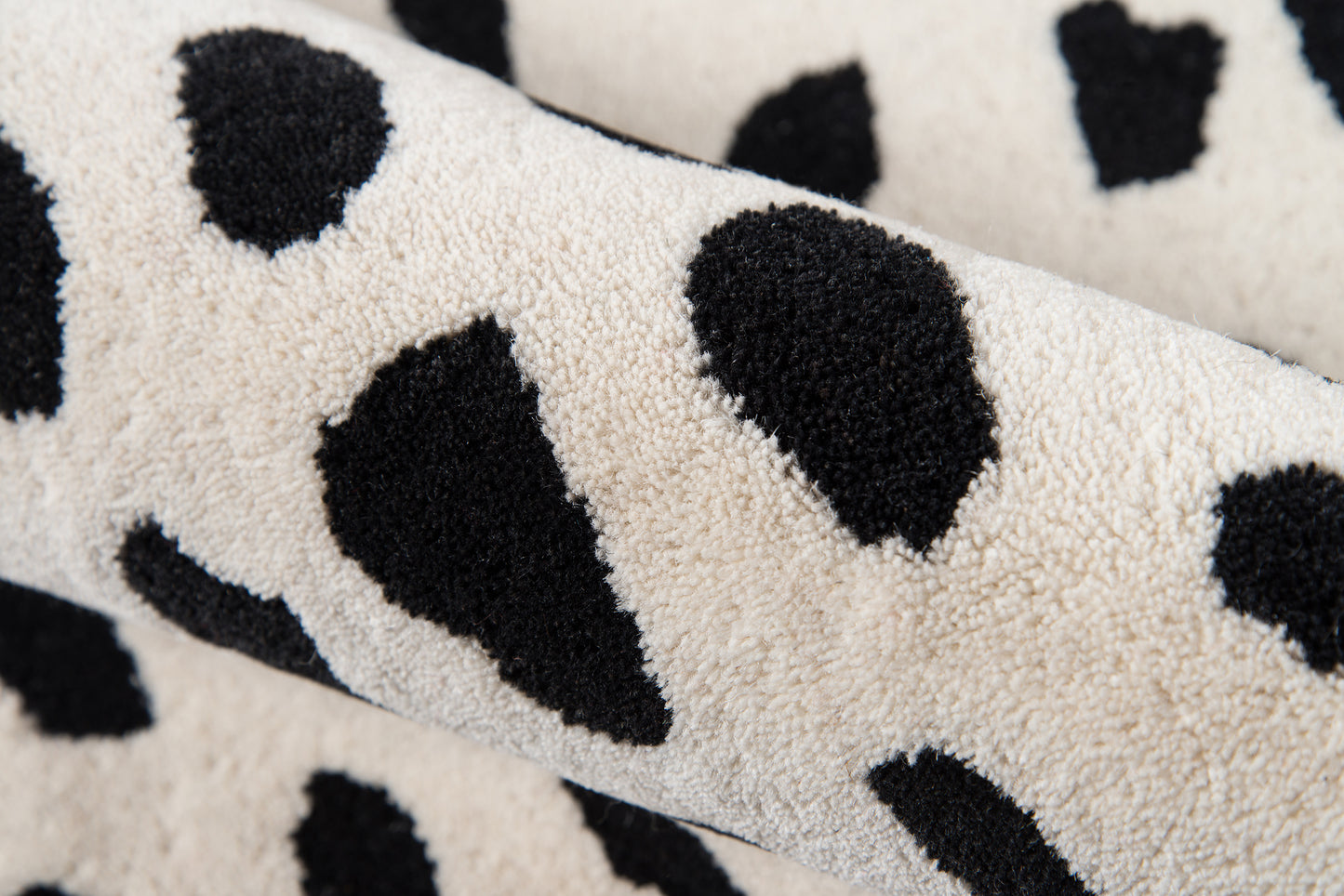 Cream faux-fur-like rug with irregular black spots.