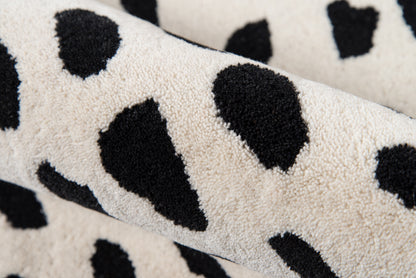 Ivory plush rug with bold black Dalmatian spots; soft, cozy decor piece.
