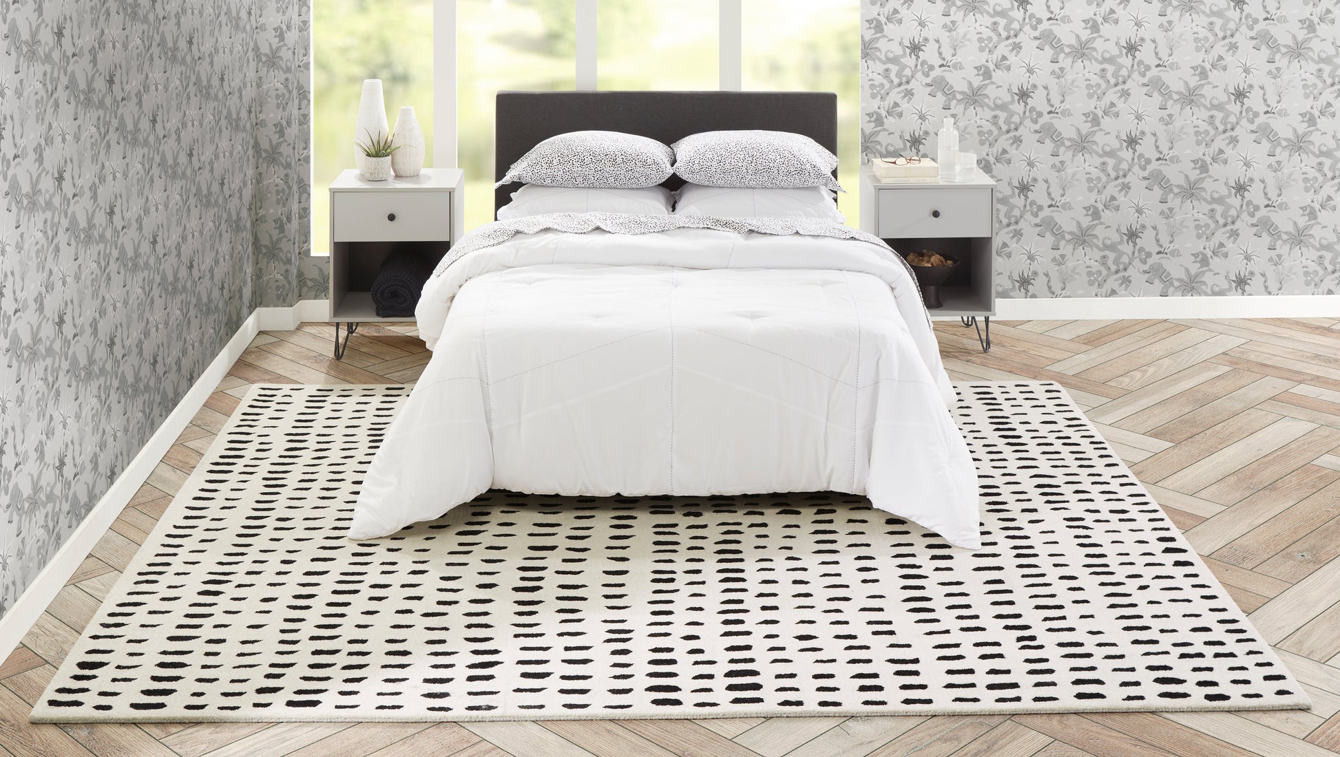 Ivory rectangular area rug with a black dot grid under a white duvet in a modern gray bedroom.