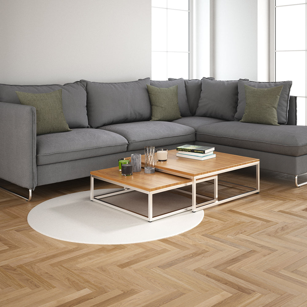 Smoke solid fabric on a grey sectional with olive cushions, two-tier wood coffee tables on white metal frames, round rug in a bright living room.
