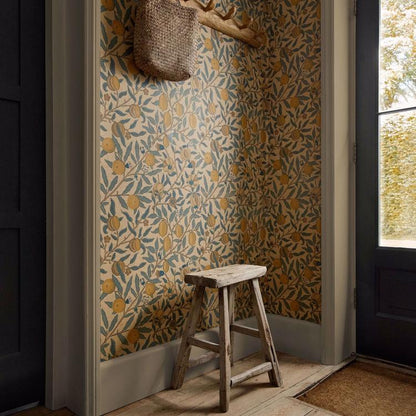 William Morris “Fruit” wallpaper in blue, gold, and brown tones showing detailed pomegranates and leaves in a classic Arts & Crafts pattern