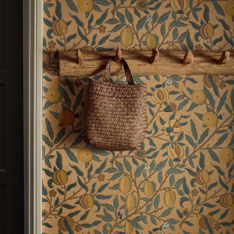 William Morris “Fruit” wallpaper in blue, gold, and brown tones showing detailed pomegranates and leaves in a classic Arts & Crafts pattern