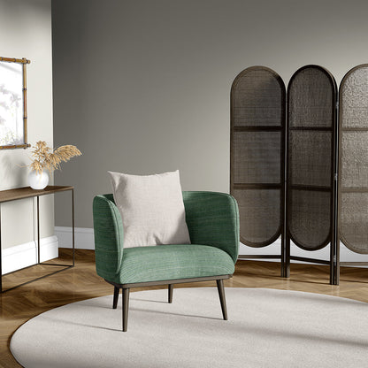 Green curved mid-century armchair upholstered in fabric with a light beige cushion and dark wooden legs in a modern living room with a wicker divider.