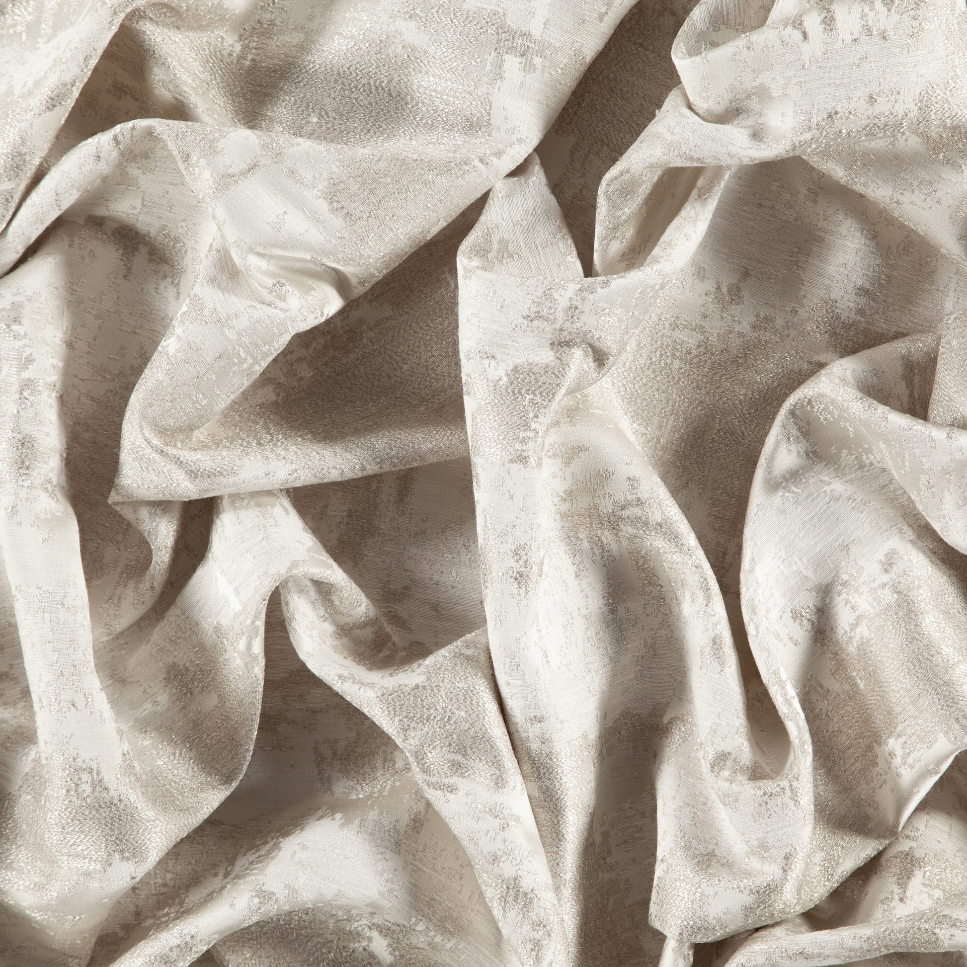 Cream-beige textured fabric with a subtle pattern, softly draped in folds.