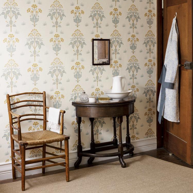 Morris & Co “Meadow Sweet” wallpaper in Gold/Slate, featuring symmetrical plant motifs and a classic Arts & Crafts style in warm gold and soft slate tones.
