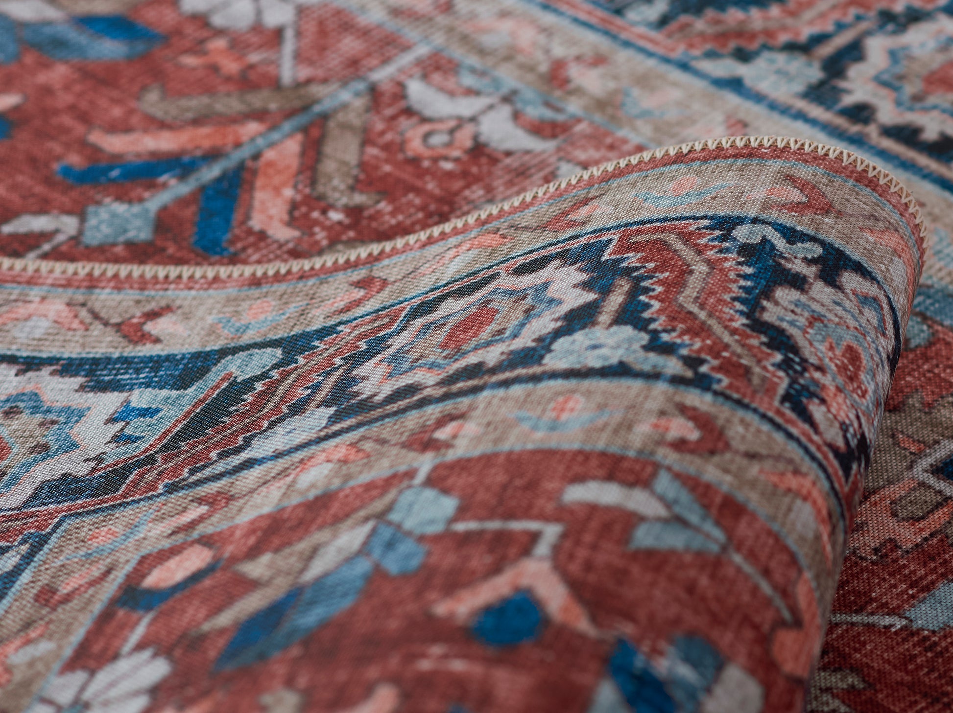 Red and blue Persian-style rug with floral motifs, woven texture, rolled edge.