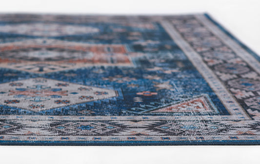 Blue oriental rug close-up with ivory and rust geometric motifs and woven texture.