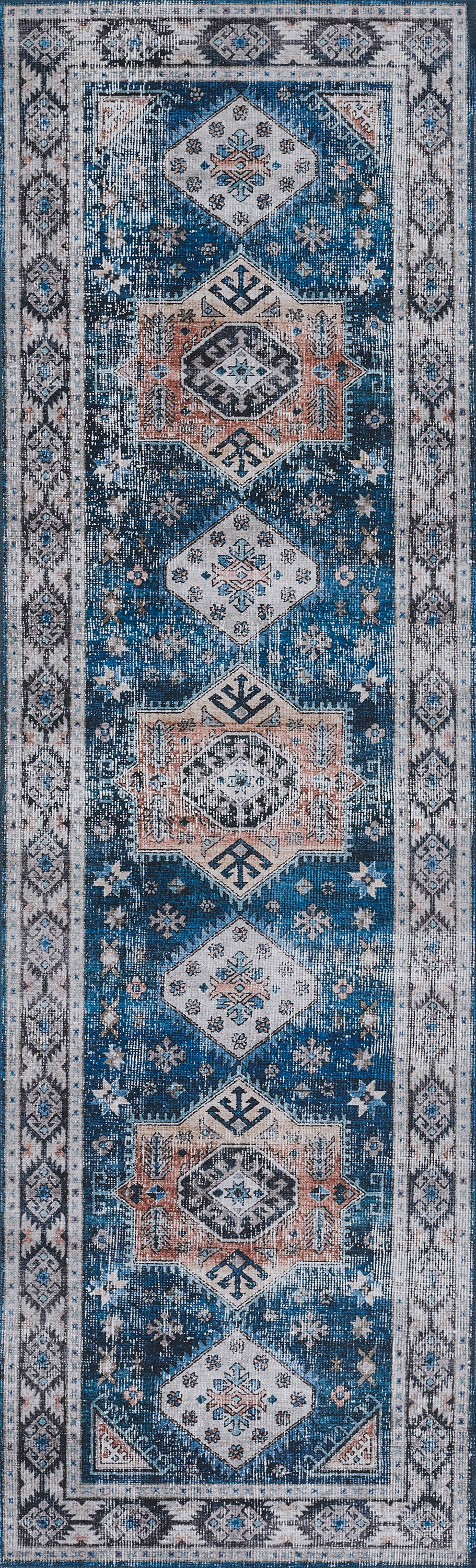 Narrow blue rug with repeating white and peach diamond medallions on a deep blue field and a light ornate border.