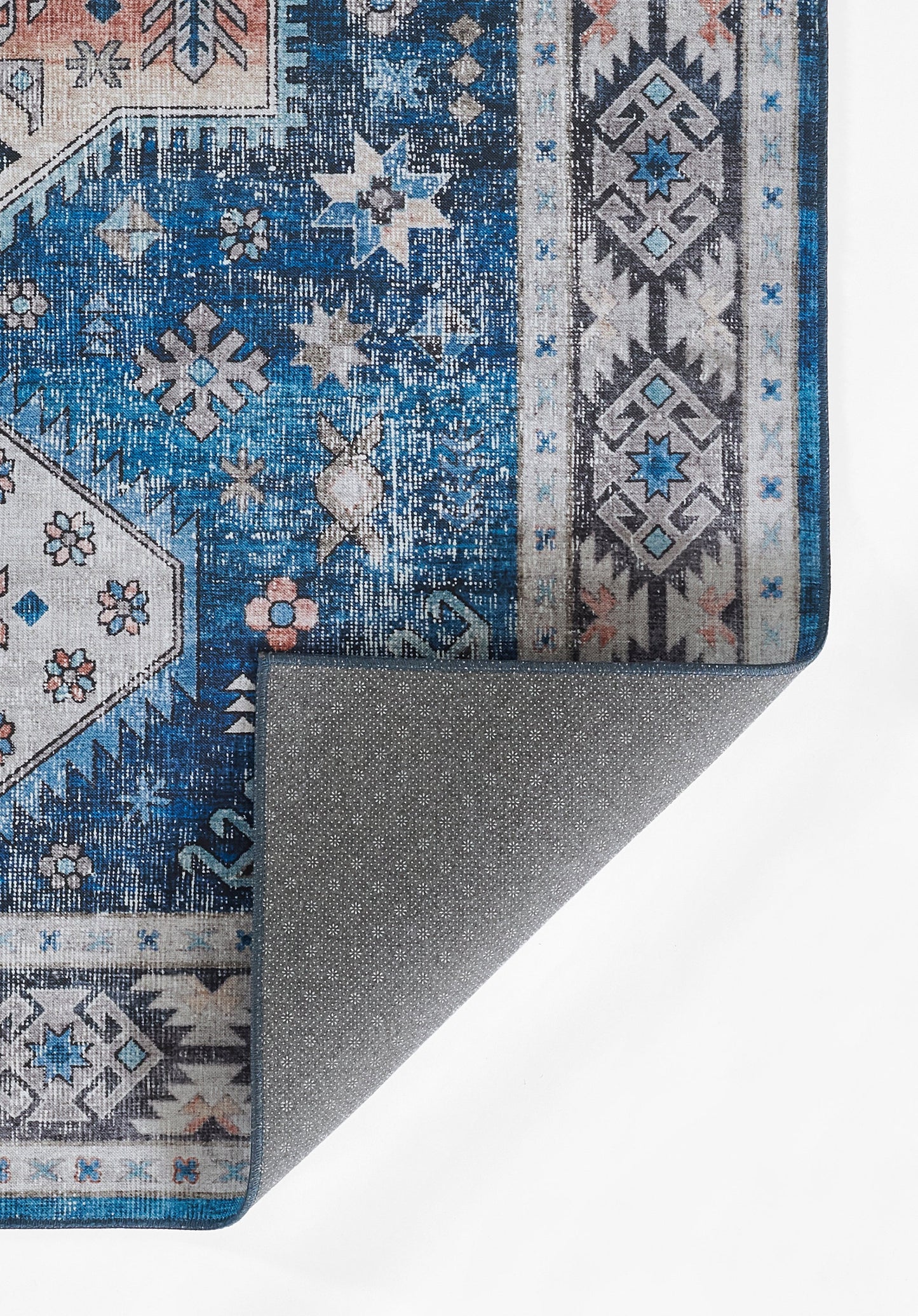Blue and ivory oriental rug with geometric borders and star motifs; folded corner reveals grey backing.