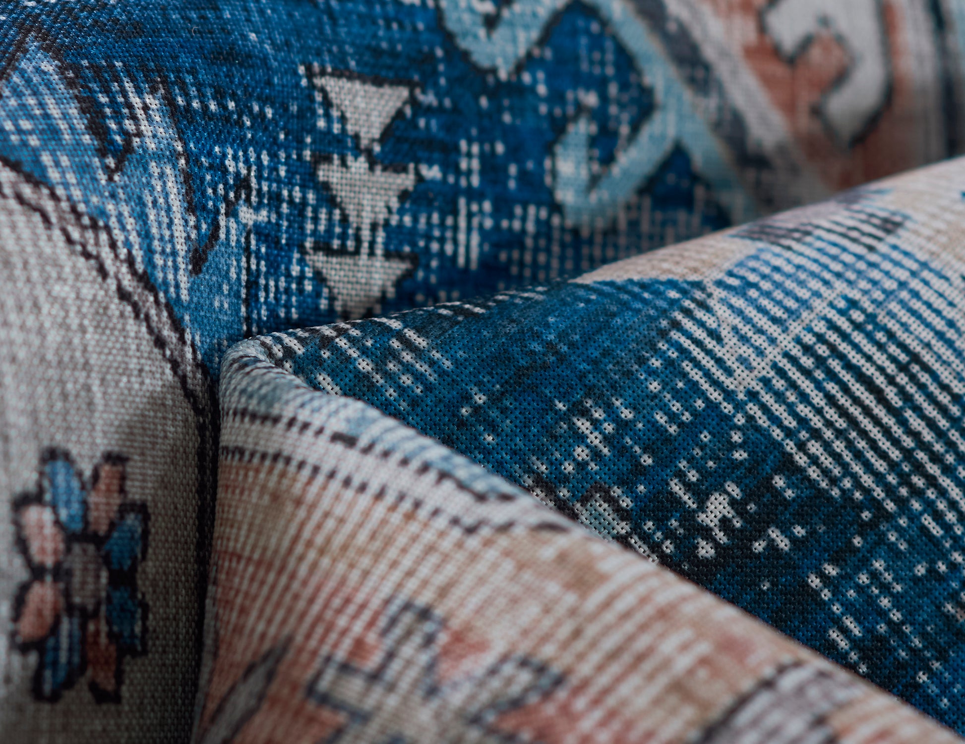Blue and beige woven rug with geometric floral motifs; textured floor covering.