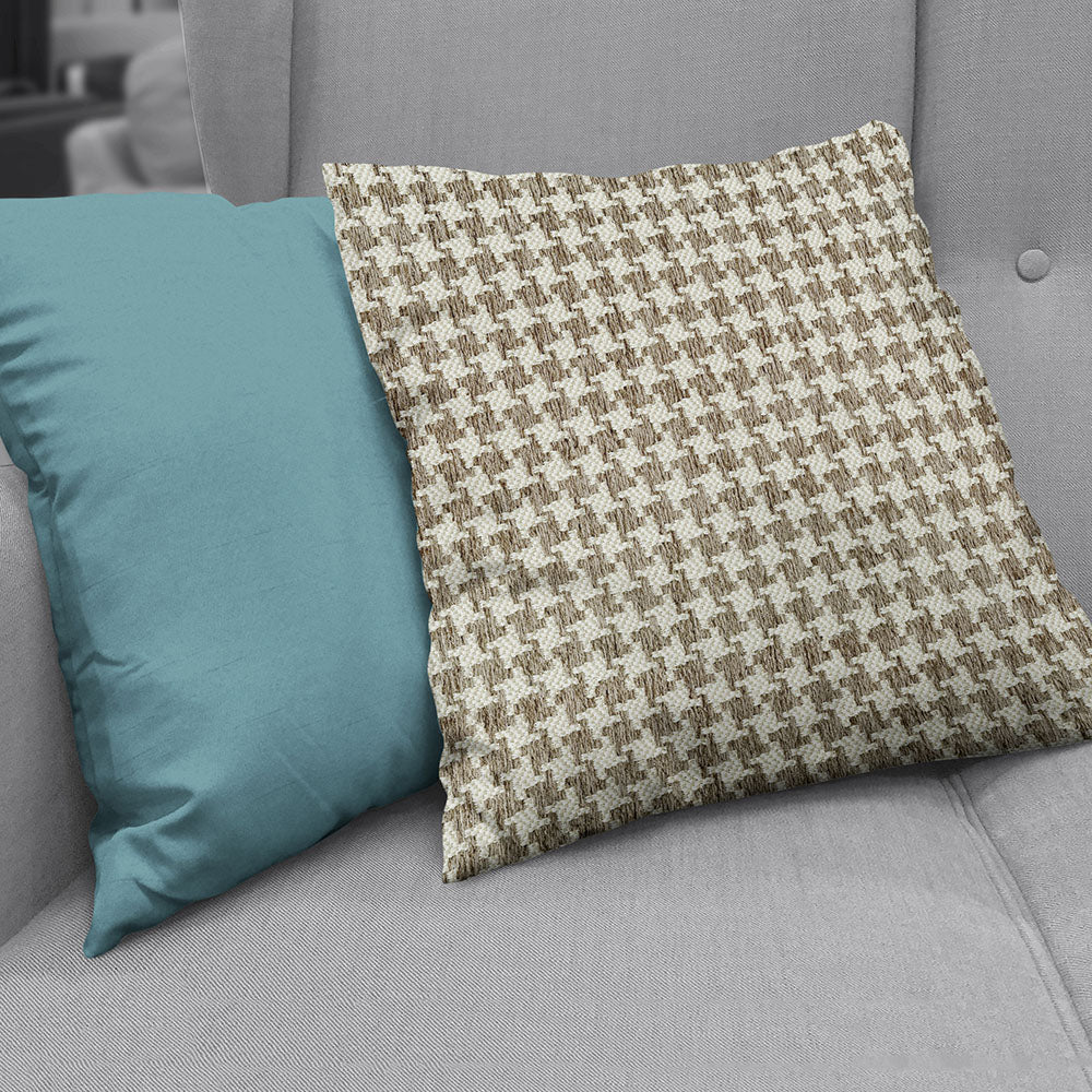 Fawn houndstooth fabric pattern on a decorative pillow resting on a gray fabric sofa