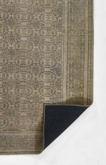 Olive-green woven rug with beige geometric medallions and decorative border; corner folded to reveal dark navy backing.