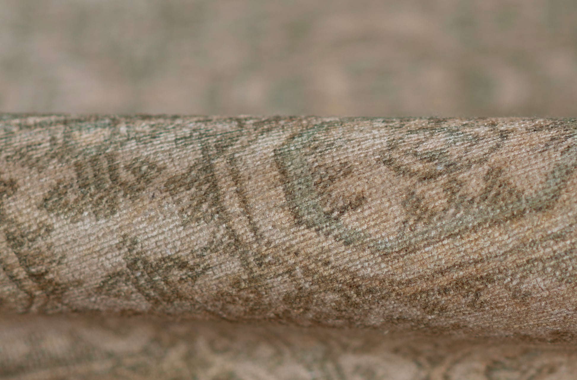 Rolled olive green & beige rug with jacquard damask pattern; woven textile for living room decor.