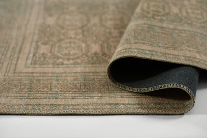 Beige patterned rug with geometric motifs, rolled corner showing dark navy underside; woven texture.