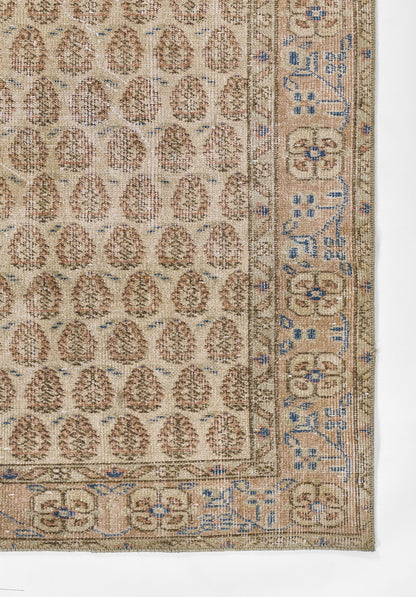 Beige oriental rug with repeating brown oval motifs and a blue geometric border; woven floor covering.