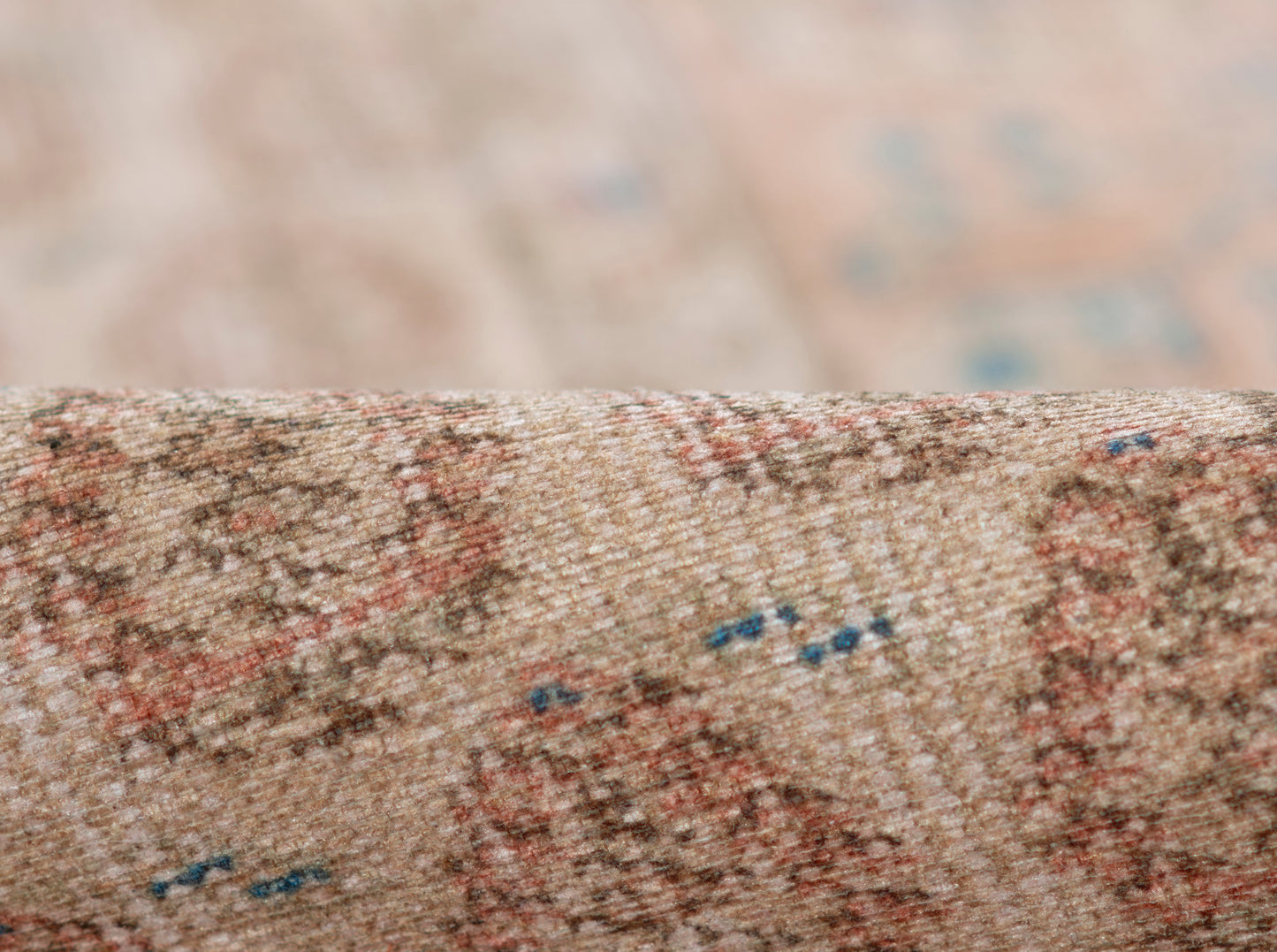 Beige Persian-style runner rug close-up with pink-red floral motifs and blue accents.